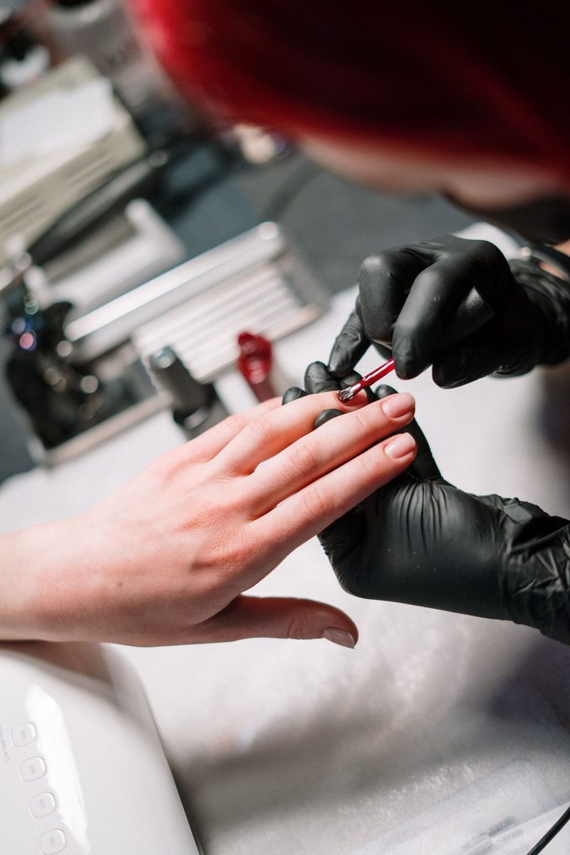 Nail technician in gloves applying gel polish
