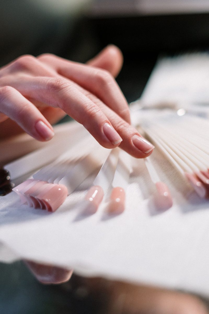 Hand holding a fan of pink nail tips